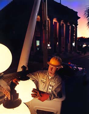photo of man changing a street lamp