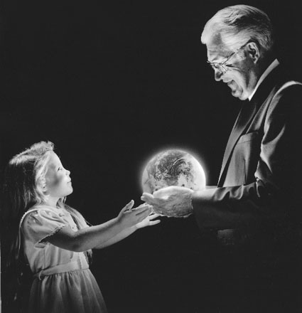 photo of an older man handing the earth to a child